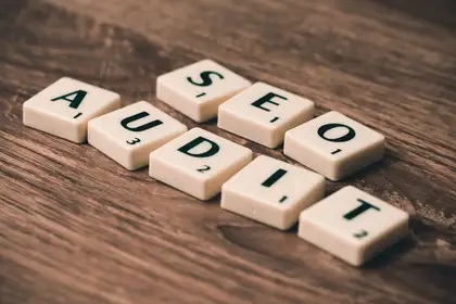 Letter tiles laid out on a wooden table spelling SEO AUDIT.